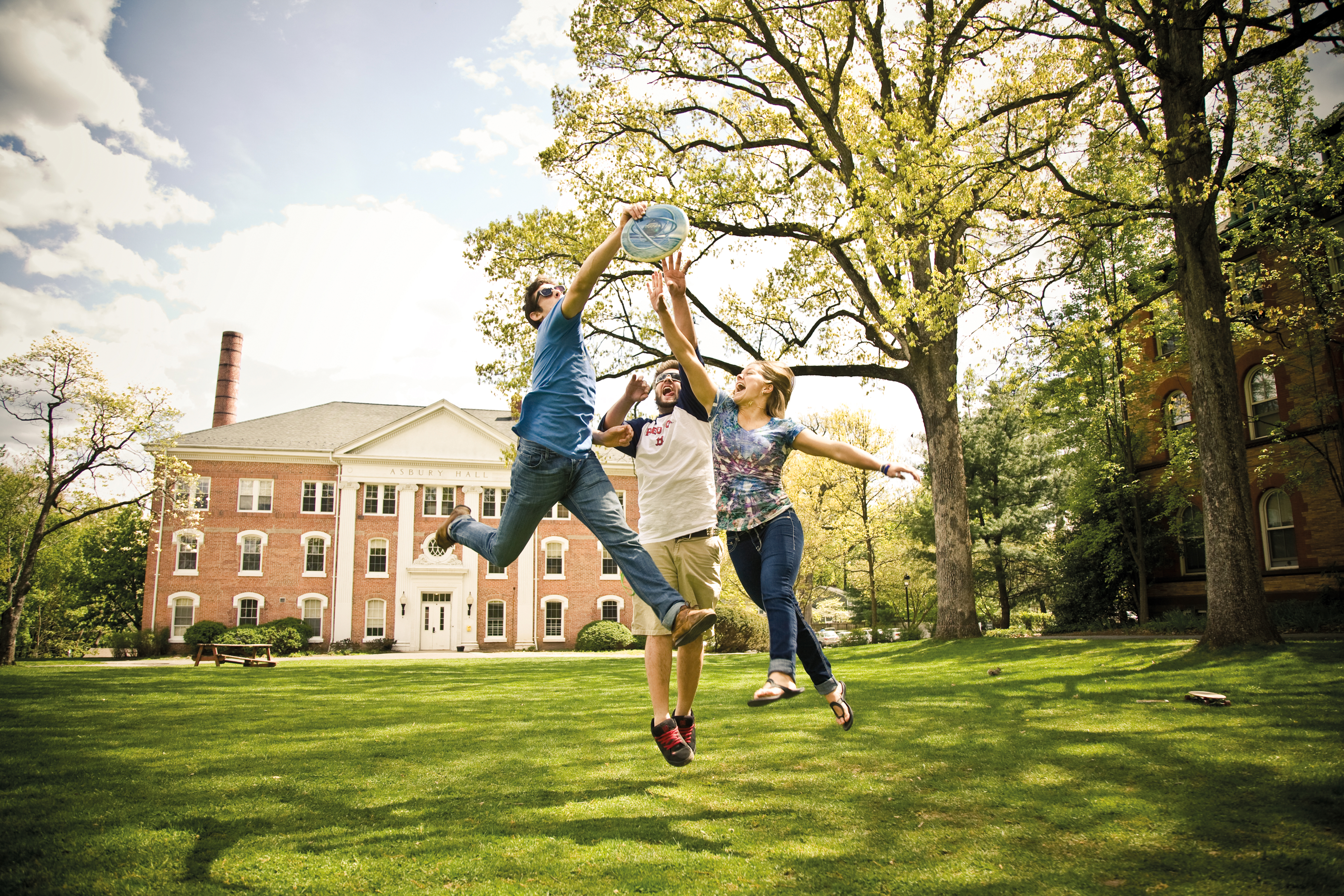 DREW three students playing freezbee outdoors in campus grounds_12295.jpg
